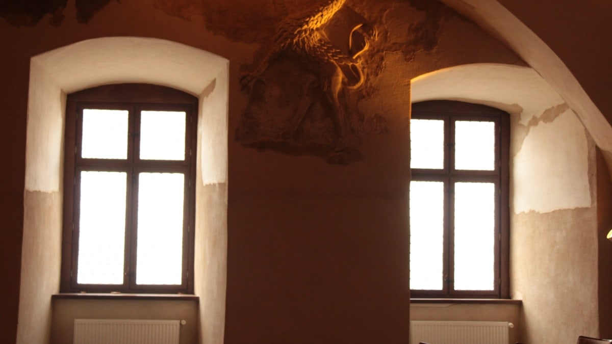 a room with two windows and a sculpture on the wall